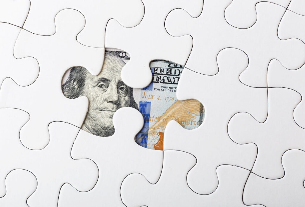 Missing puzzle piece with money under it signifying litigation funding is the missing link to a legal case